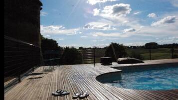 Een seizoensgebonden buitenzwembad en ligstoelen