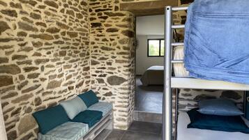 A room with stone walls, a bunk bed, and a sofa with cushions.
