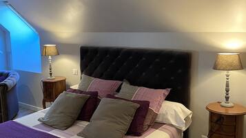 A neatly made bed with a dark headboard, two bedside tables with lamps, and a window with blinds.