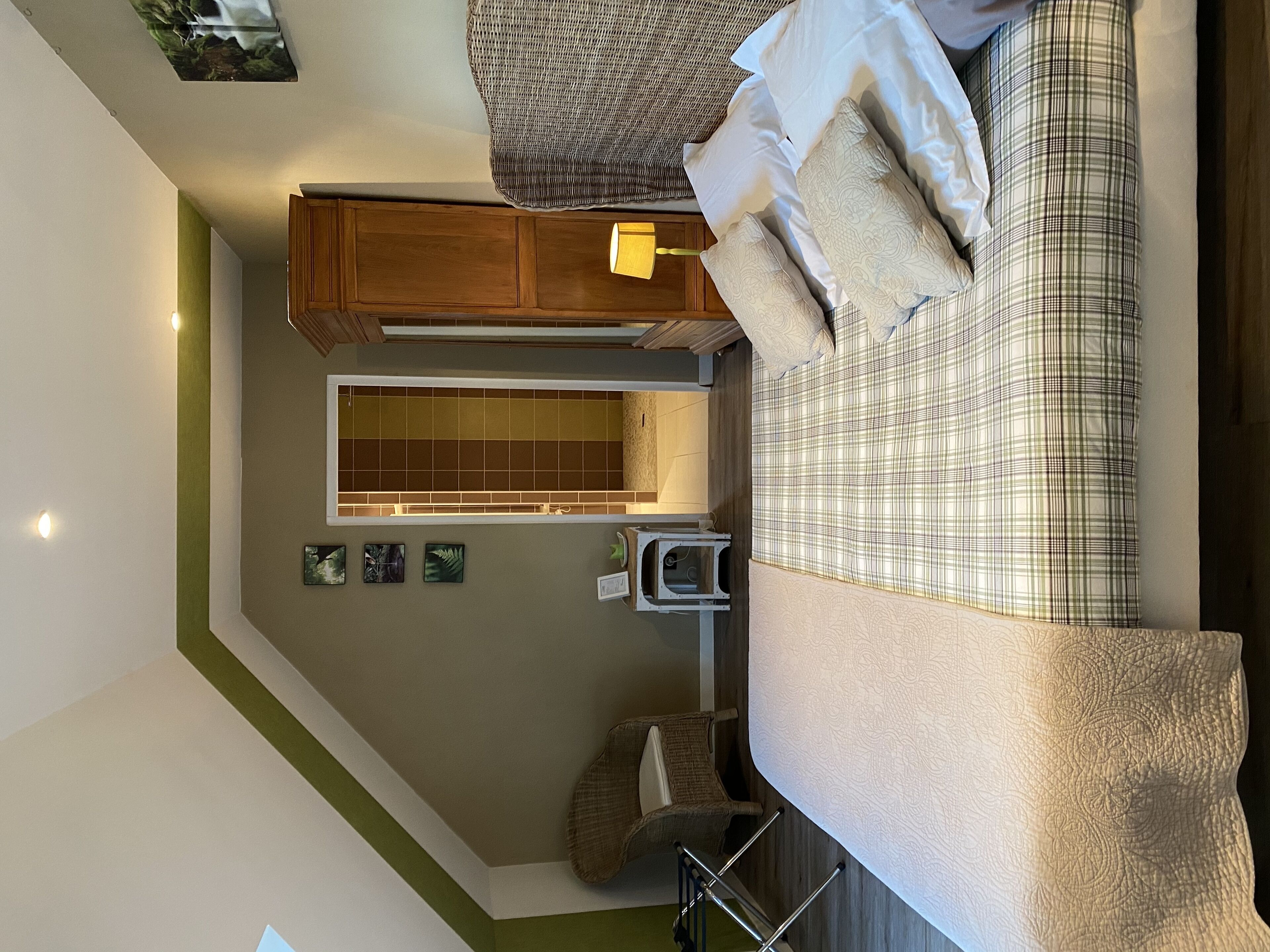 A bedroom with a large bed, a chair, a wardrobe, and a small table.