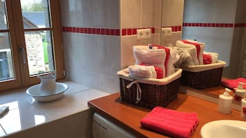 Une salle de bain avec un plan de toilette en bois, un lavabo et un lave-linge. On y trouve des serviettes et des articles de toilette sur le plan de toilette.