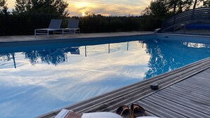 Vista de la piscina con sillas de descanso y un libro abierto.