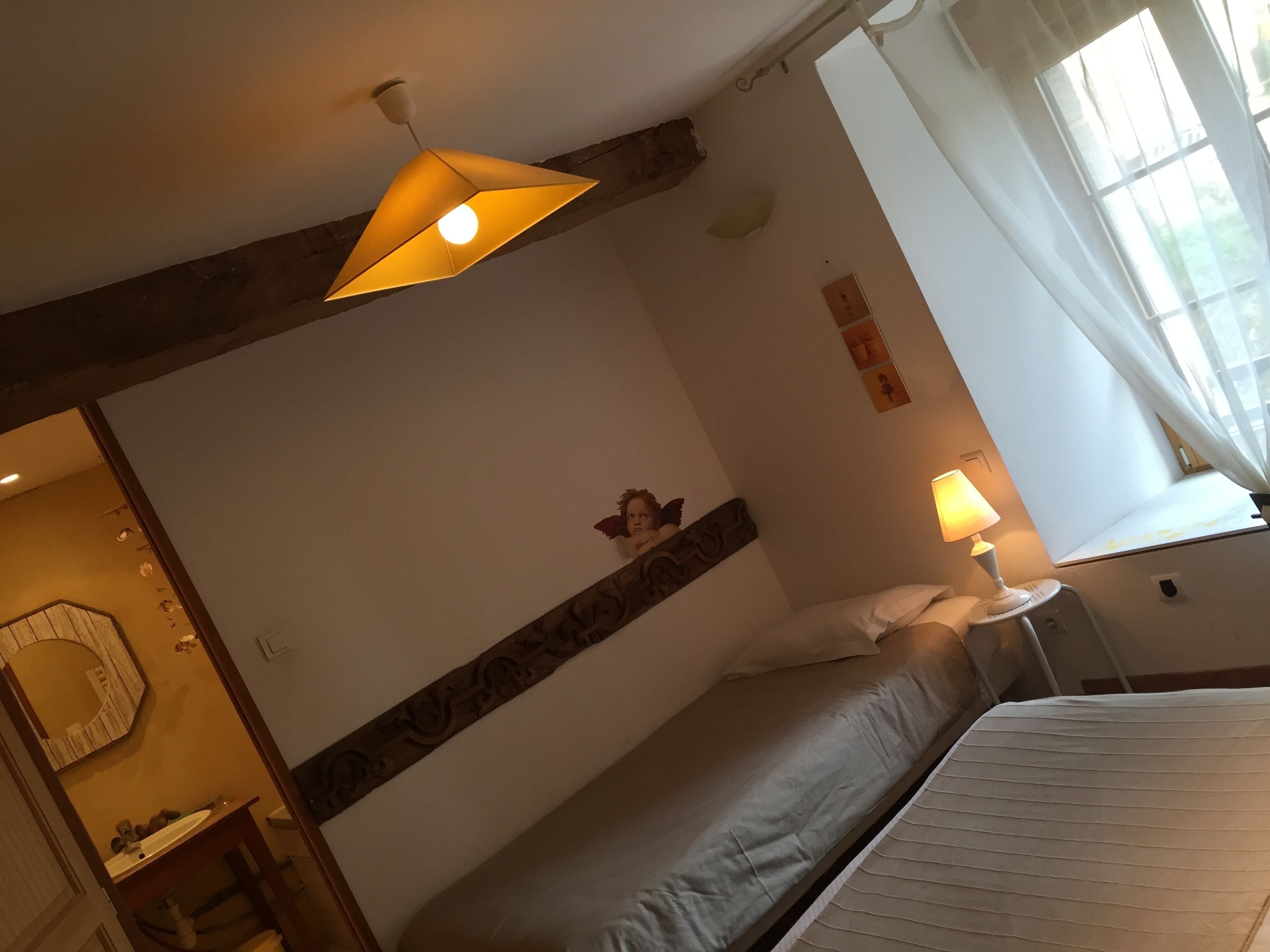 A hotel room with a bed, a nightstand with a lamp, a mirror, and a decorative wall piece.