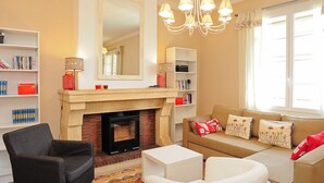 A living room with a fireplace, a sofa, a chair, and a bookshelf. - Air-conditioned apartment 100m2 garage terrace near Avignon center (Avignon)