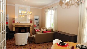 A cozy living room with a fireplace, a dining table set with plates and glasses, a sofa with cushions, and a bookshelf. - Air-conditioned apartment 100m2 garage terrace near Avignon center (Avignon)