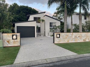 A modern two-story house with a garage, stone walls, and a well-maintained lawn.