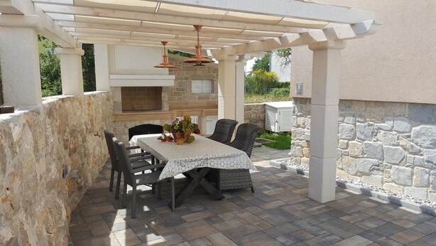 An outdoor patio with a stone wall, a pergola, a table with chairs, and a built-in grill. - Apartments Villa Rustica (ST) - Two-Bedroom Apartment with Balcony and Shared Pool (groundfloor) (Zadar)