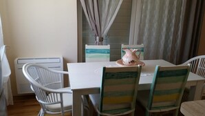 A dining area with a white table, striped chairs, a pitcher, and a window with curtains. - Apartments Villa Rustica (ST) - Two-Bedroom Apartment with Balcony and Shared Pool (groundfloor) (Zadar)