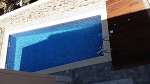 A rectangular swimming pool with clear blue water, surrounded by a stone wall and wooden deck. - Apartments Villa Rustica (ST) - Two-Bedroom Apartment with Balcony and Shared Pool (groundfloor) (Zadar)