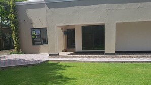 A modern building with a flat roof, large windows, and a well-maintained lawn. - Pizo Lodge (Kabwe)