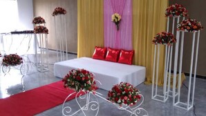 A room with a white bed, red pillows, yellow curtains, and floral arrangements. - Pizo Lodge (Kabwe)