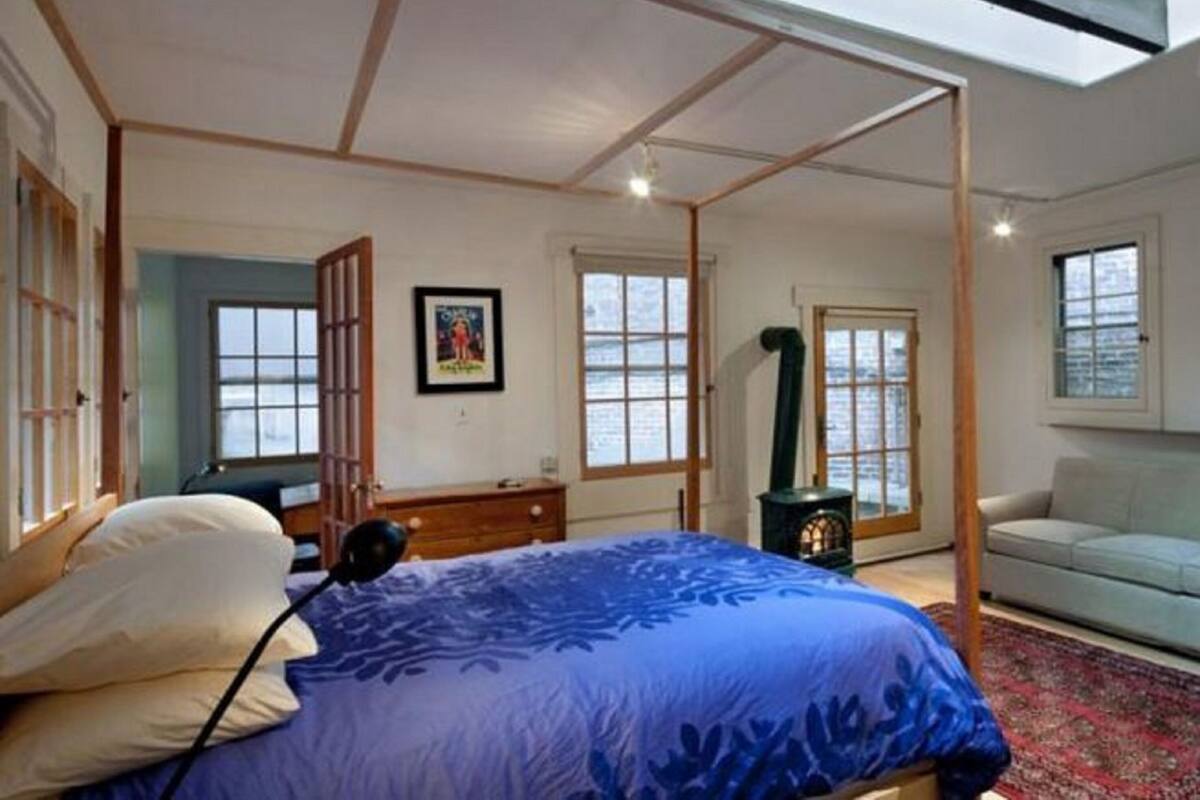 A bedroom with a four-poster bed, a desk, a chair, and a sofa.