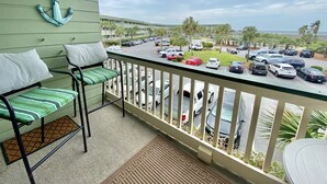 Ein Balkon mit zwei Stühlen, Blick auf einen Parkplatz und ein Gebäude im Hintergrund mit Palmen.