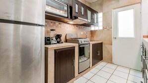 A compact kitchen with a refrigerator, stove, microwave, and cabinets.