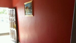 A hallway with red walls and a white floor, leading to a door with a metal gate. - Mwayose Lodge (Lusaka)