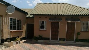 A building with a tiled driveway and a satellite dish. - Mwayose Lodge (Lusaka)