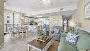 Un vaste espace de vie comprenant une table à manger, des canapés et un ventilateur de plafond.