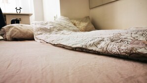 A bed with a patterned blanket and pillows, a bedside table with a decorative item, and a window with curtains. - Ultra Central apartment (Oradea)
