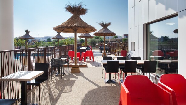 A rooftop terrace with outdoor seating, umbrellas, and a view of the city.