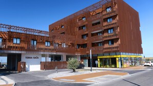 A modern building with a unique facade, a parking area, and a storefront with signage.