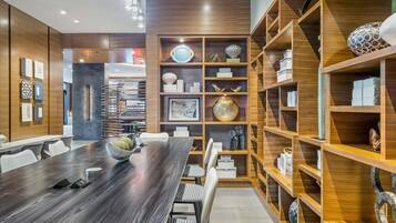 A modern meeting room with a long wooden table, white chairs, and built-in wooden shelving with decorative items.