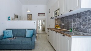 A modern kitchen with white cabinets, a wooden countertop, and a tiled backsplash.