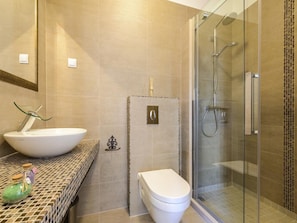 Features a large vessel sink, sleek toilet, and glass-enclosed shower area.