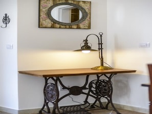 Relax in a serene space with a wooden table, vintage lamp, and elegant mirror.