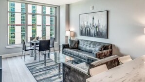 Una sala de estar moderna con una mesa de comedor de vidrio, un sofá de cuero y un amplio ventanal con vista a la ciudad.
