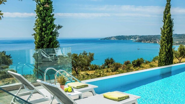A poolside area with lounge chairs and a glass-enclosed structure overlooking a body of water. - Villa Della Luna - Three Bedroom Villa, Sleeps 6 (Vlachata)