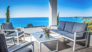 A balcony with a view of the sea, furnished with a sofa, chairs, and a coffee table. - Villa Della Luna - Three Bedroom Villa, Sleeps 6 (Vlachata)