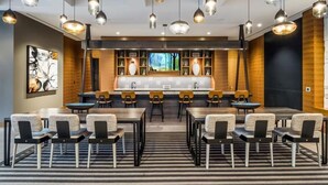 A modern hotel lobby with a central bar area, multiple seating arrangements, and pendant lighting. - Modern Luxury in Reston |  In-unit Washer/D | nr Dulles Airport (Reston)