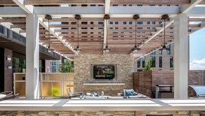 A modern outdoor bar area with a stone wall, seating, and a television screen. - Modern Luxury in Reston |  In-unit Washer/D | nr Dulles Airport (Reston)