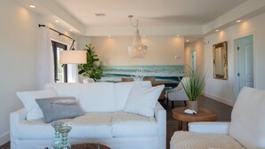 Ein modernes Wohnzimmer mit einem weißen Sofa, einem Couchtisch und einem Gemälde, das den Ozean zeigt.