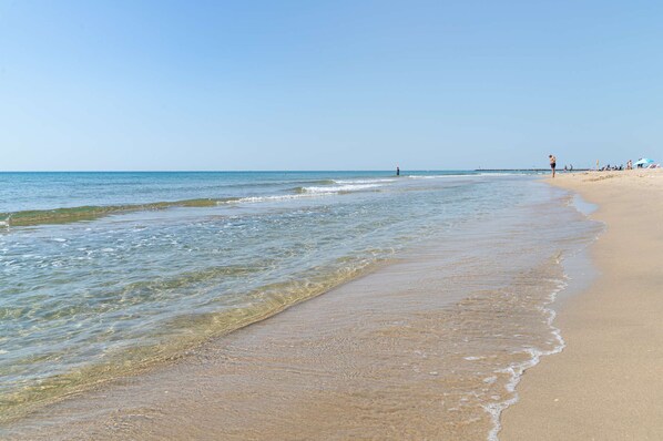 A beach with clear water, a sandy shore, and a few people in the distance. - Beautiful residence (MARSEILLAN PLAGE)