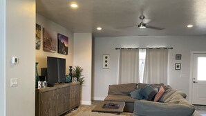 A modern living room with a grey sectional sofa, a wooden cabinet, and a flat-screen TV. - Sand Hollow Retreat (Hurricane)