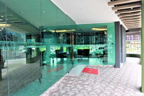 Ein modernes Interieur mit Glaswänden, einem gemusterten Boden und einer roten Fußmatte.