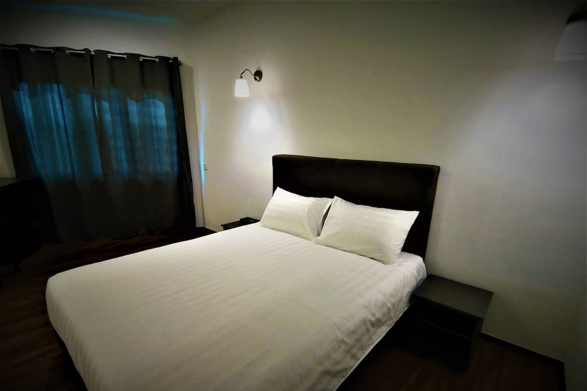 A neatly made bed with white linens in a hotel room.