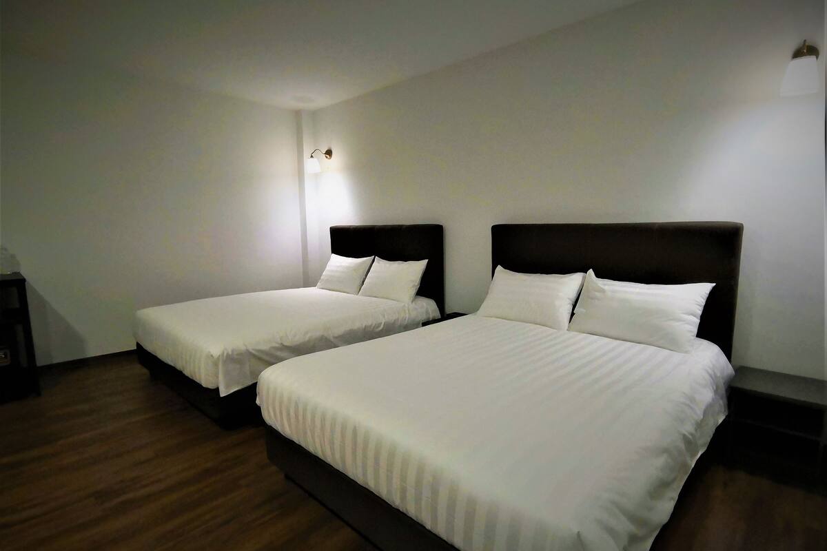 Two single beds with dark headboards in a room with wooden flooring and white walls.