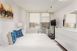 Relax in a spacious room with a large bed, flat-screen TV, and city view.
