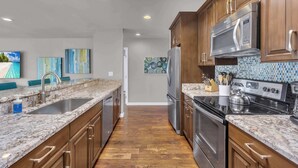 Una cocina moderna con gabinetes de madera, electrodomésticos de acero inoxidable y salpicadero de azulejos.