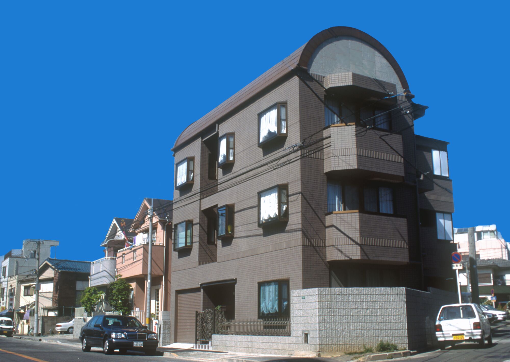 A multi-story building with a curved roof, several windows, and a gated entrance.