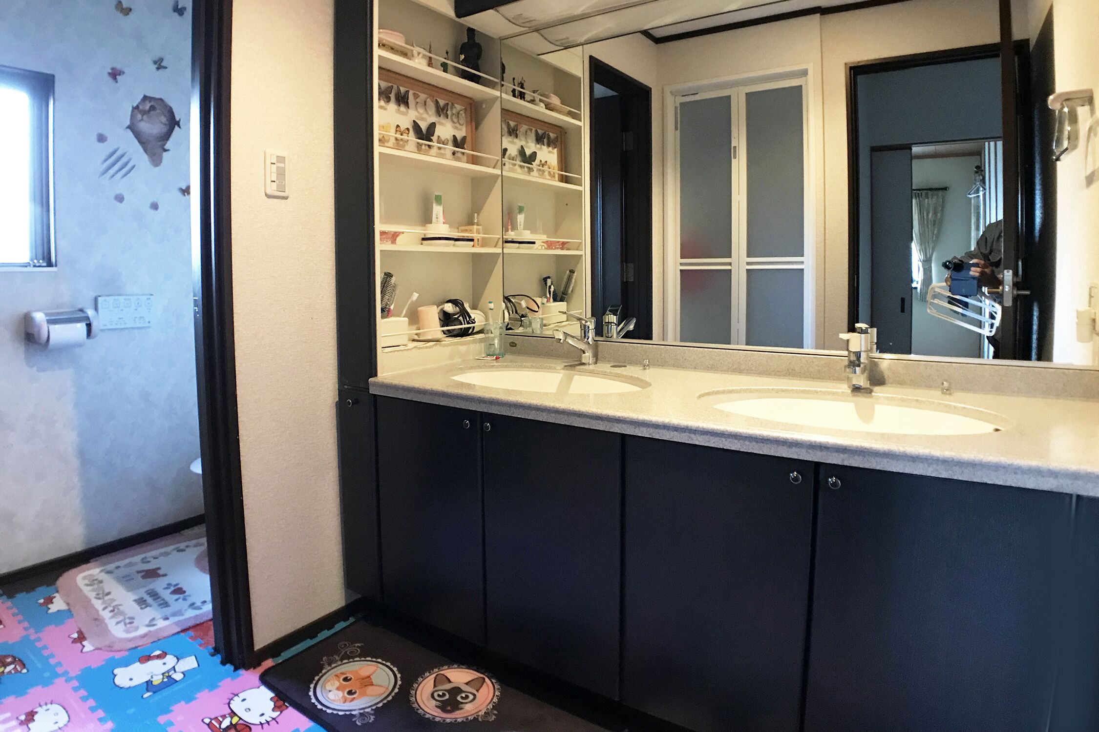 A bathroom with two sinks, a mirror, and shelves above the sinks.