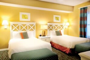Two single beds with geometric-patterned headboards, each with green and orange pillows, are accompanied by bedside tables and lamps.