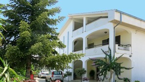 Un edificio de dos pisos con un patio central, balcones y plantas en macetas.