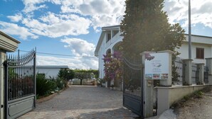 Una entrada empaveda de piedra a una propiedad con camino de acceso porticado, un edificio blanco y un cartel.