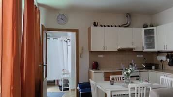 A kitchen with white cabinets, a clock, and a dining area with a table and chairs.