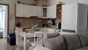 Cozinha compacta com armários brancos, uma mesa de jantar e um sofá.