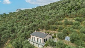 Een huis op een heuvel, met een gevel van natuursteen, groene luiken en een balkon.