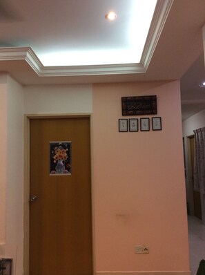 Comfortable room with a simple layout, featuring a wall-mounted outlet and framed artwork.